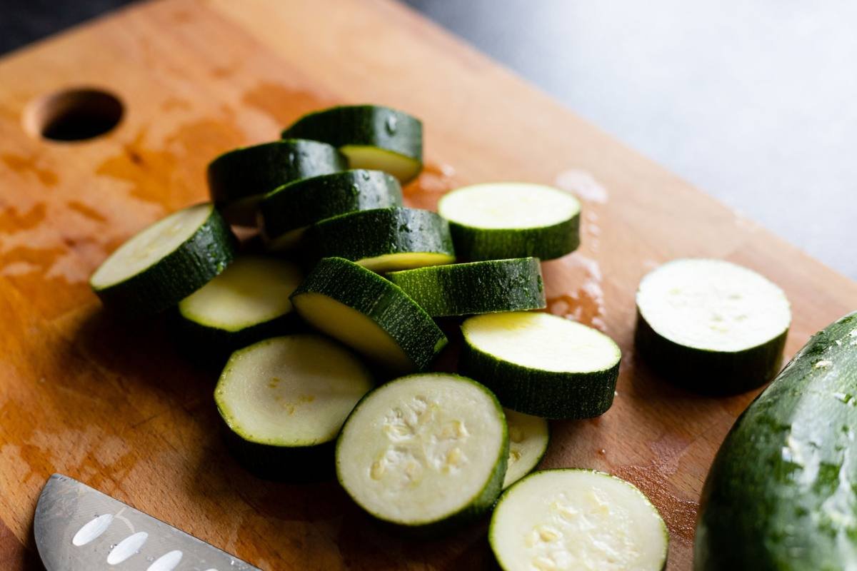 Doorgesneden courgette op een houten snijplank, met een mes ernaast